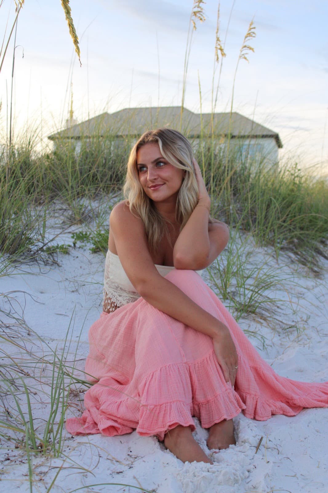 Devyn McCreery sitting in the sea oats on white sand at sunset